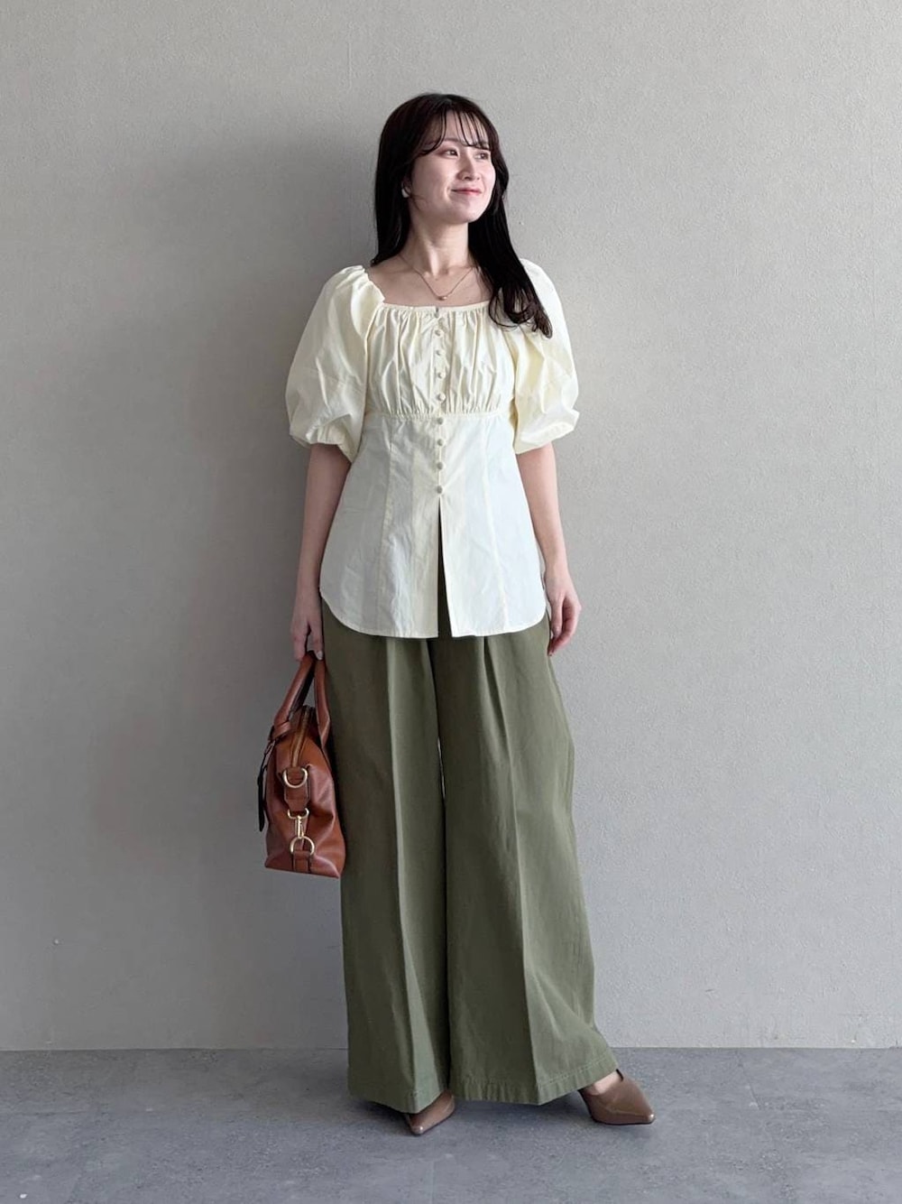 ブラウン系のボストンバッグ、ブラウン系のサンダル、ホワイト系のシャツ/ブラウスを着用したレディースの春コーディネートの1枚目の写真