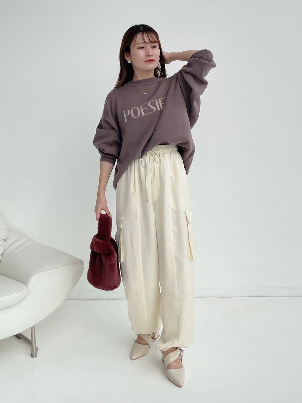 ホワイト系のパンプス、ピンク系のハンドバッグ、ブラウン系のニット/セーターを着用したレディースの秋コーディネートの1枚目の写真