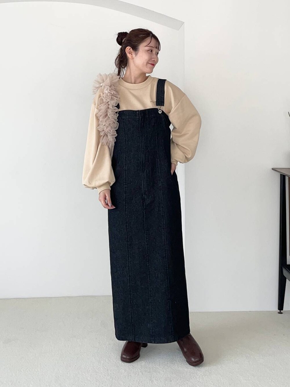 ブラック系のジャンパースカート、ベージュ系のショルダーバッグ、ブラウン系のブーツを着用したレディースの秋コーディネートの1枚目の写真