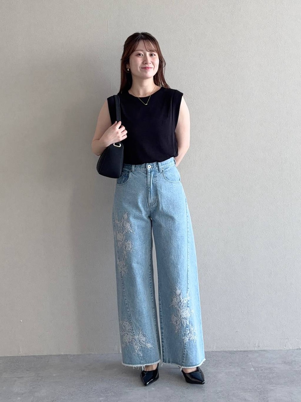 ブラック系のニット/セーター、ブルー系のデニムパンツ、ブラック系のサンダルを着用したレディースの夏コーディネートの1枚目の写真