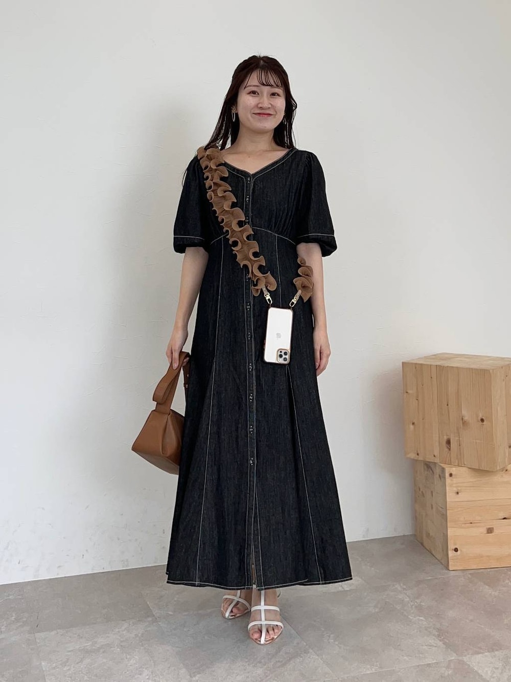 ブラウン系のショルダーバッグ、ブラック系のワンピース、ホワイト系のサンダルを着用したレディースの春コーディネートの1枚目の写真