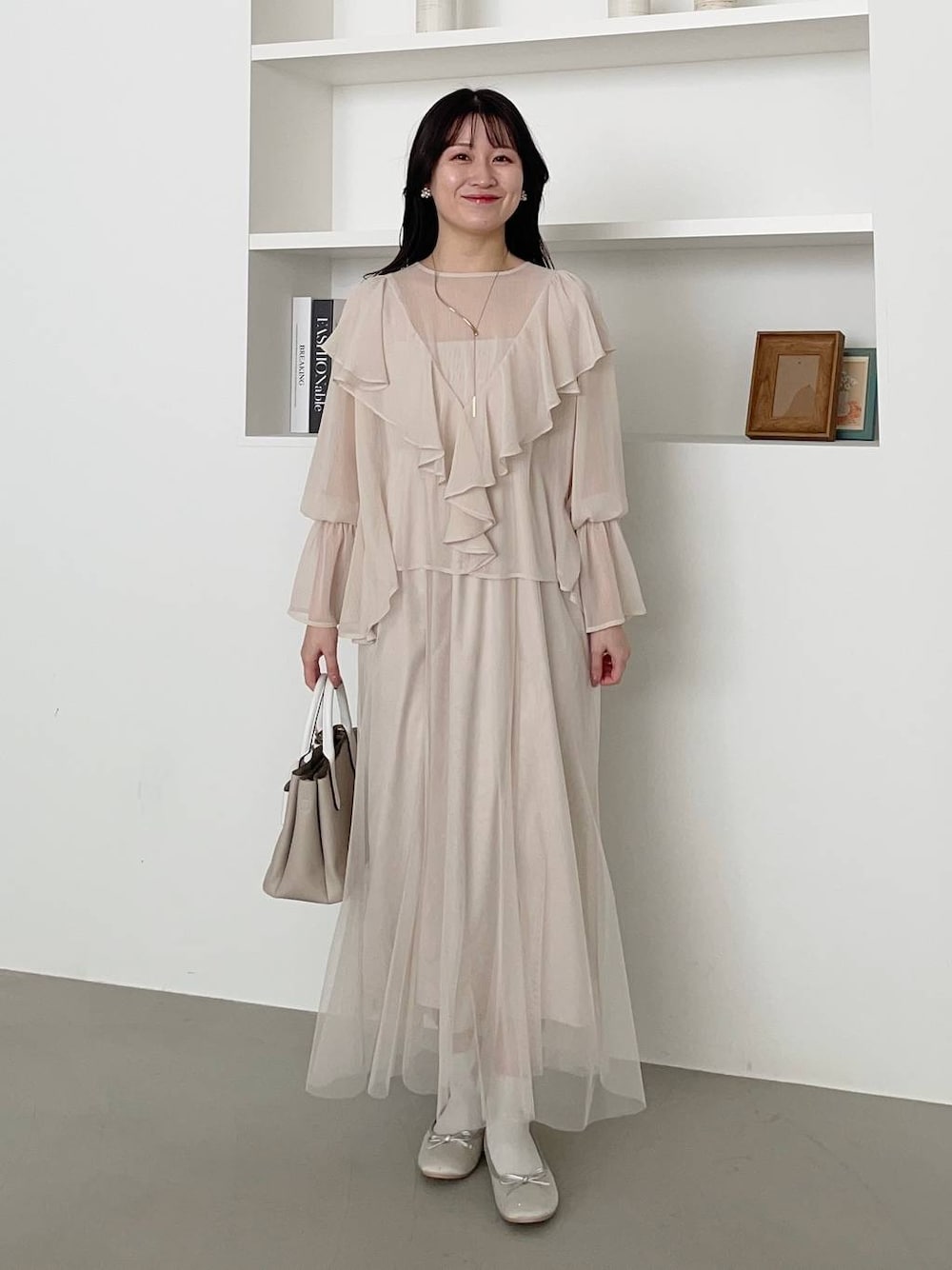 ベージュ系のショルダーバッグ、シルバー系のバレエシューズ、ホワイト系のワンピースを着用したレディースの春コーディネートの1枚目の写真