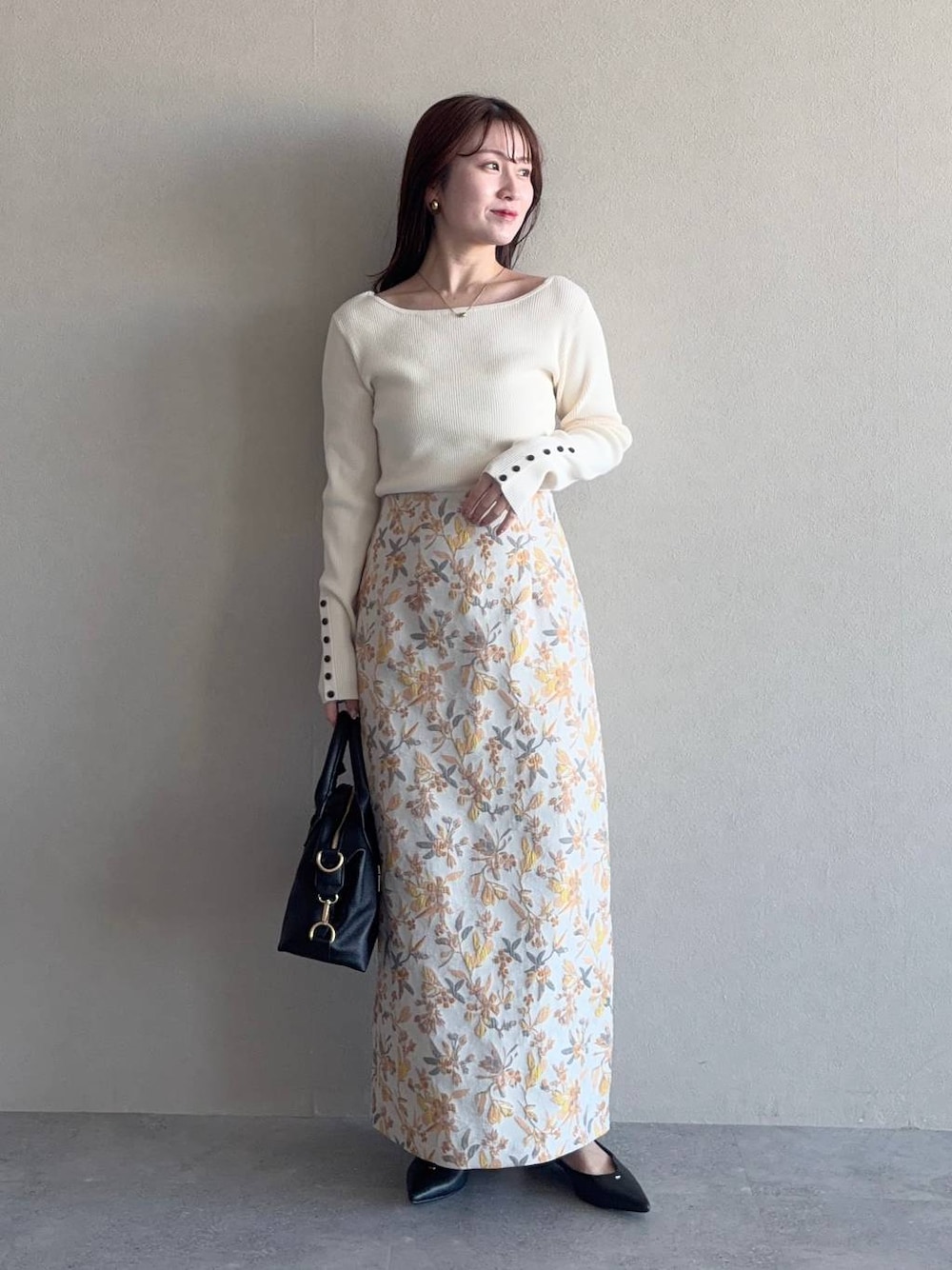 ブラック系のボストンバッグ、ホワイト系のスカート、ブラック系のパンプスを着用したレディースの冬コーディネートの1枚目の写真