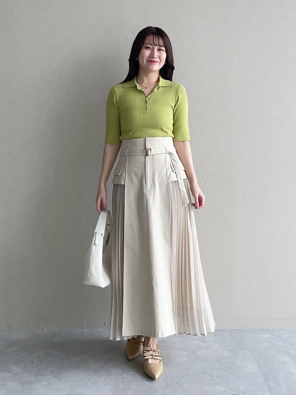 ホワイト系のスカート、グリーン系のニット/セーター、ホワイト系のショルダーバッグを着用したレディースの春コーディネートの1枚目の写真