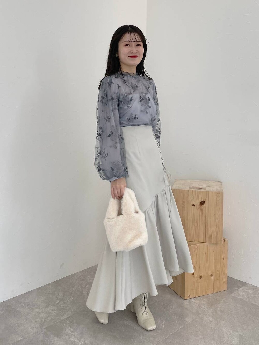 ホワイト系のブーツ、ブルー系のシャツ/ブラウス、ホワイト系のハンドバッグを着用したレディースの冬コーディネートの1枚目の写真