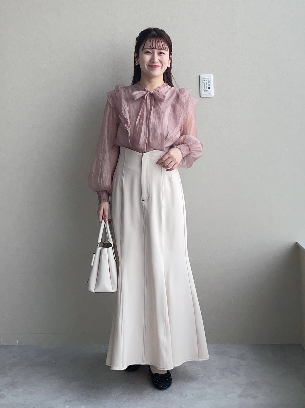 ホワイト系のショルダーバッグ、ブラック系のバレエシューズ、ホワイト系のスカートを着用したレディースの冬コーディネートの1枚目の写真