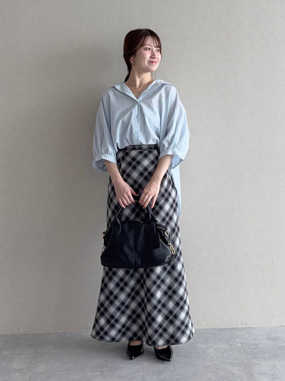 ブルー系のシャツ/ブラウス、グレー系のスカート、ブラック系のボストンバッグを着用したレディースの夏コーディネートの1枚目の写真