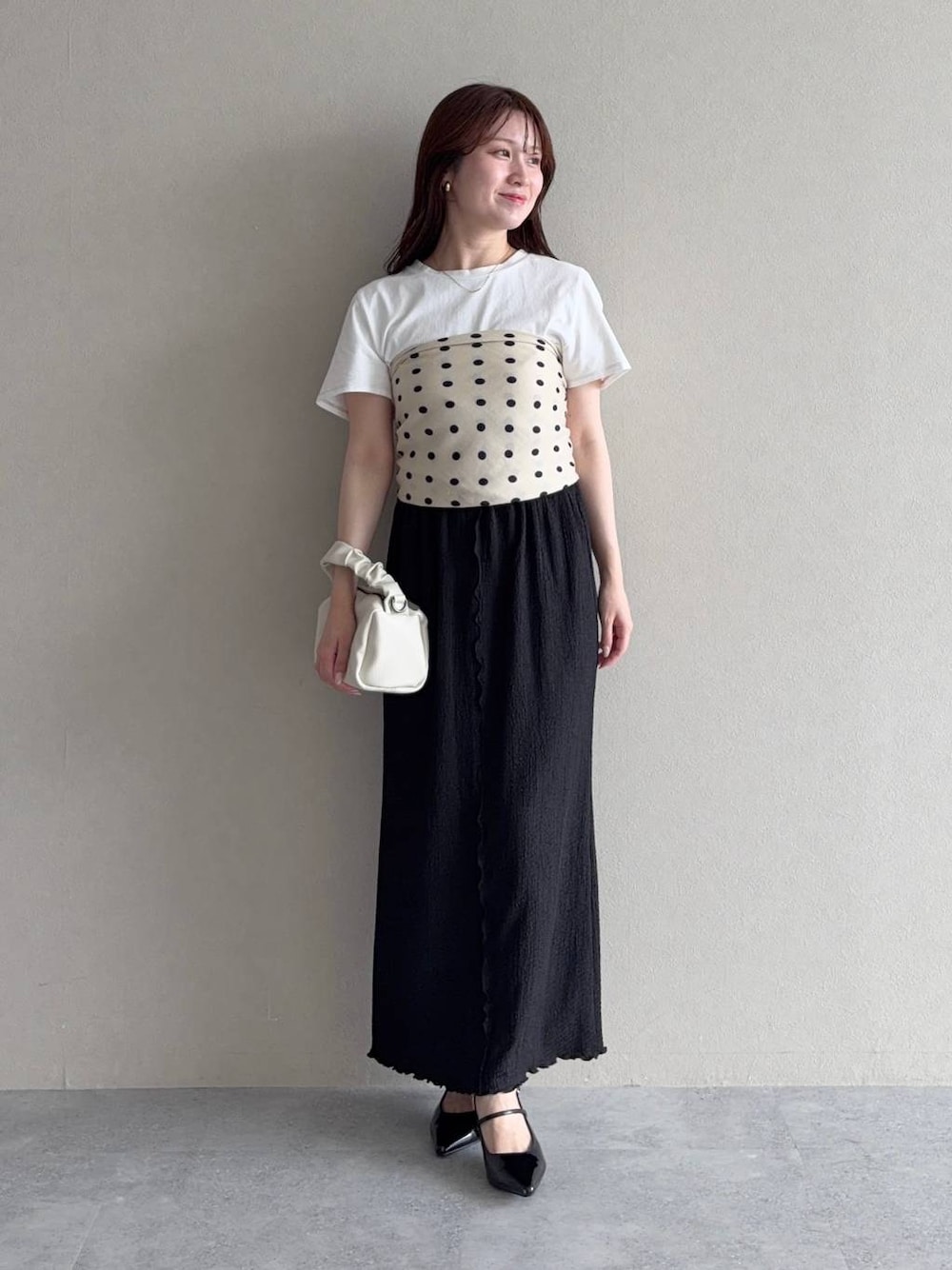 ブラック系のスカート、ブラック系のサンダル、ホワイト系のTシャツ/カットソーを着用したレディースの夏コーディネートの1枚目の写真