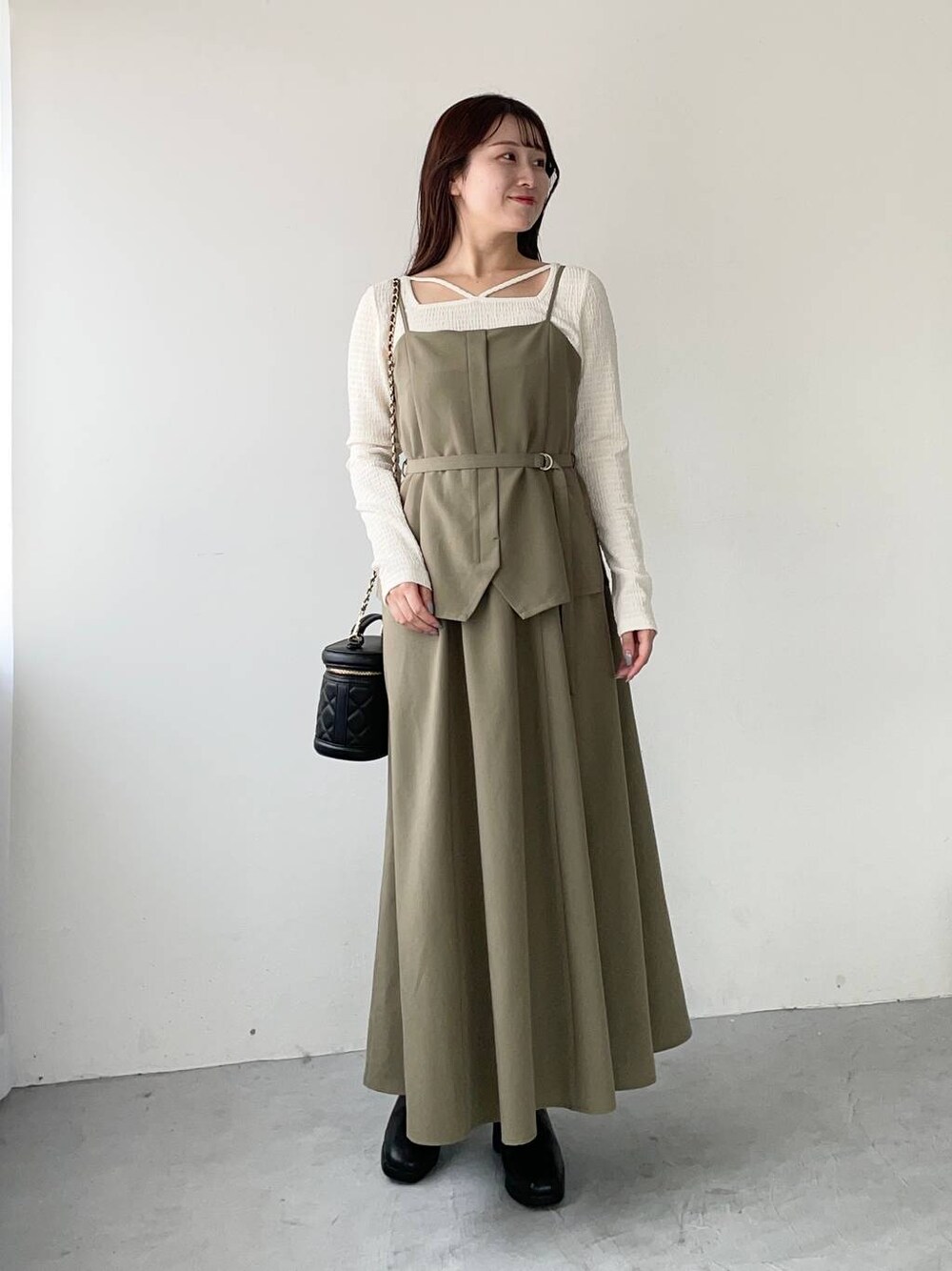 ブラウン系のワンピース、ブラック系のブーツ、ホワイト系のTシャツ/カットソーを着用したレディースの秋コーディネートの1枚目の写真