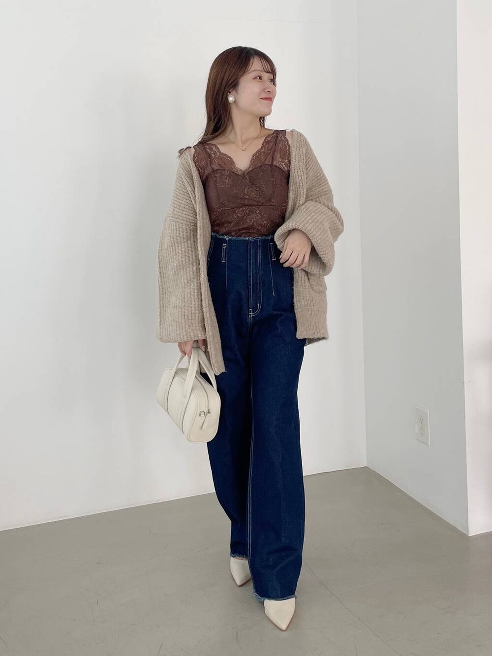 ブルー系のデニムパンツ、ホワイト系のボストンバッグ、ホワイト系のパンプスを着用したレディースの秋コーディネートの1枚目の写真