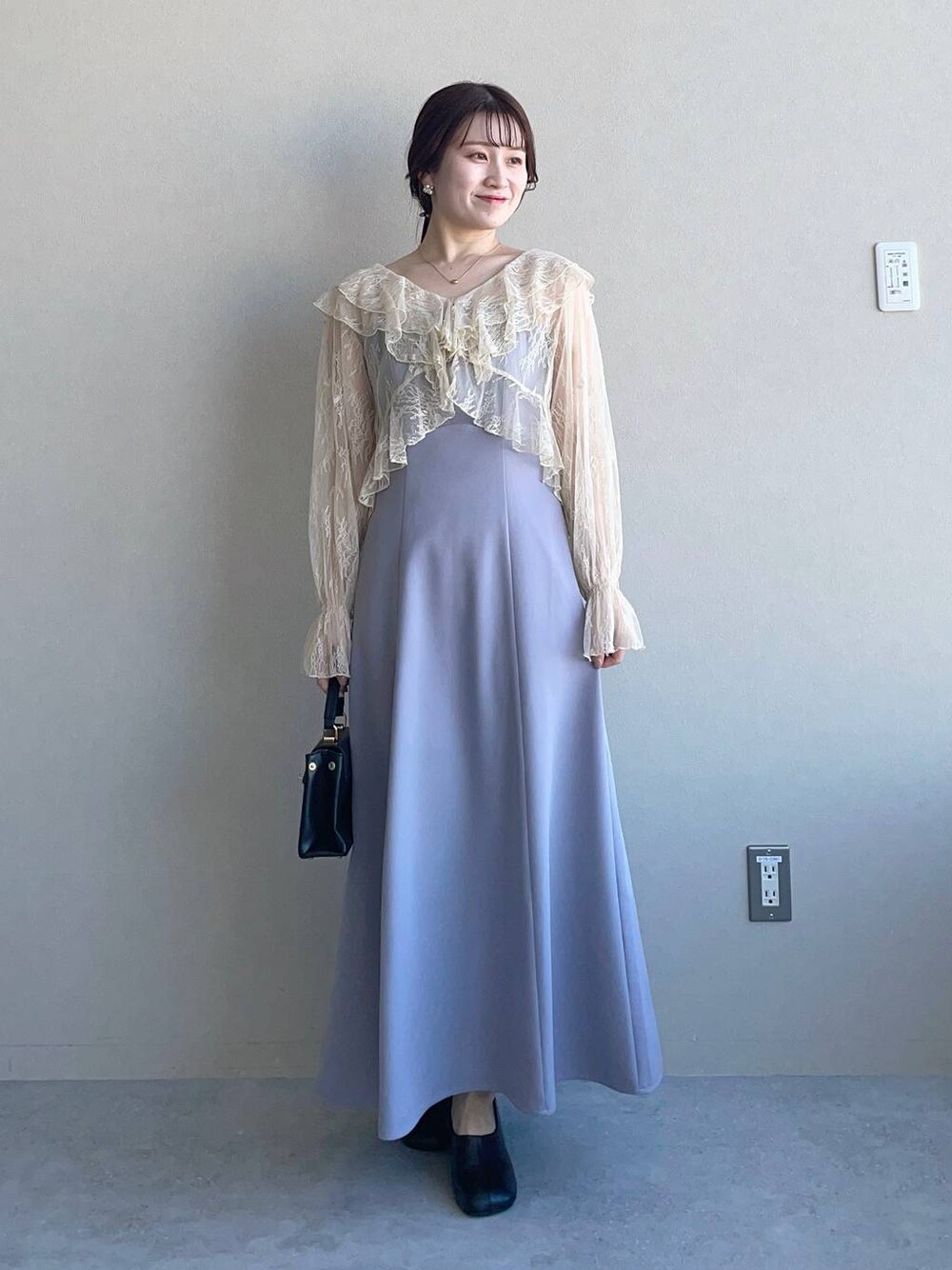 ブラック系のパンプス、グレー系のドレスを着用したレディースの冬コーディネートの1枚目の写真