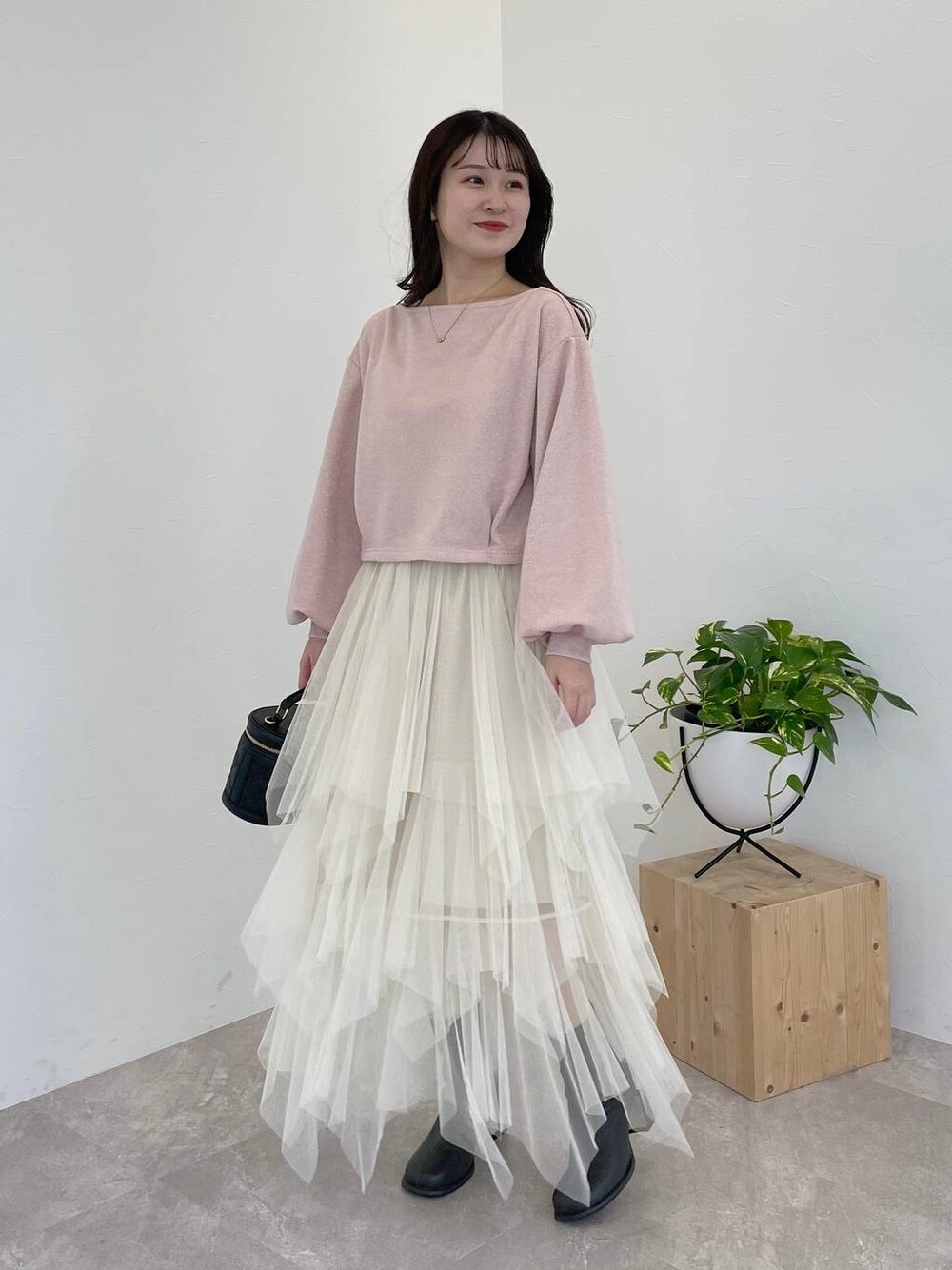 グレー系のブーツ、ブラック系のショルダーバッグ、ホワイト系のスカートを着用したレディースの冬コーディネートの1枚目の写真