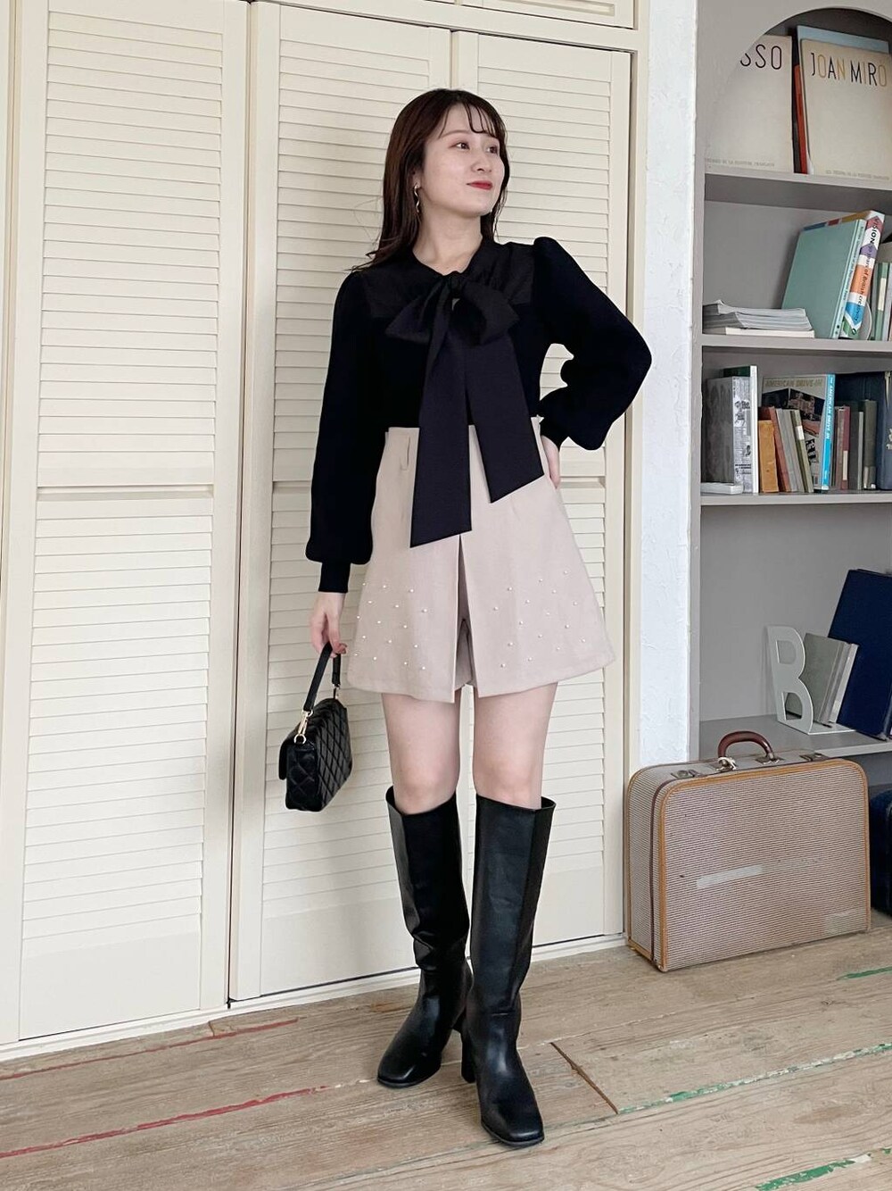 ブラック系のブーツ、ブラック系のニット/セーター、ベージュ系のその他パンツを着用したレディースの冬コーディネートの1枚目の写真