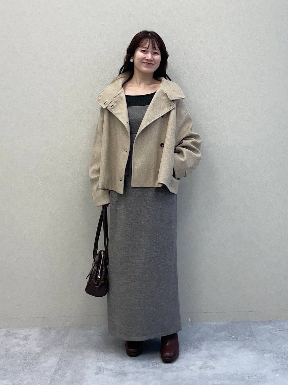 ベージュ系のピーコート、ブラウン系のブーツ、グレー系のワンピースを着用したレディースの秋コーディネートの1枚目の写真