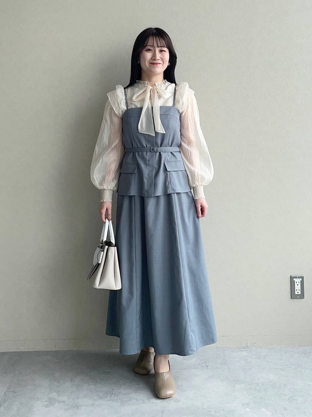 ベージュ系のショルダーバッグ、ブラウン系のパンプス、ホワイト系のシャツ/ブラウスを着用したレディースの春コーディネートの1枚目の写真