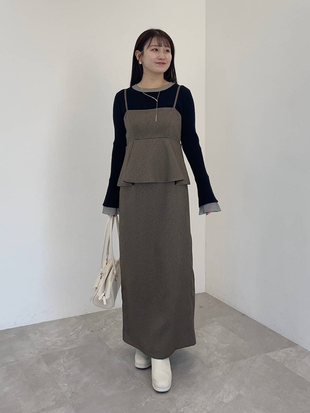 ホワイト系のブーツ、ブラウン系のワンピース、ホワイト系のハンドバッグを着用したレディースの冬コーディネートの1枚目の写真