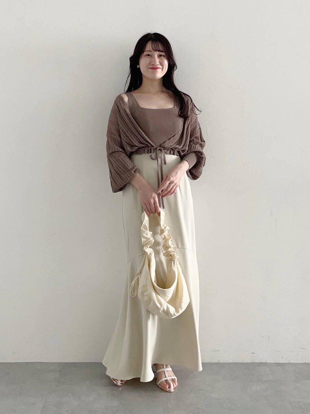 ホワイト系のショルダーバッグ、ホワイト系のスカート、ホワイト系のサンダルを着用したレディースの春コーディネートの1枚目の写真