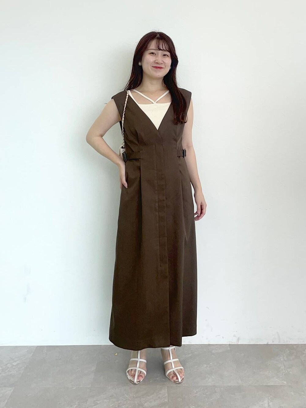 ブラウン系のジャンパースカート、ホワイト系のショルダーバッグ、ホワイト系のニット/セーターを着用したレディースの夏コーディネートの1枚目の写真