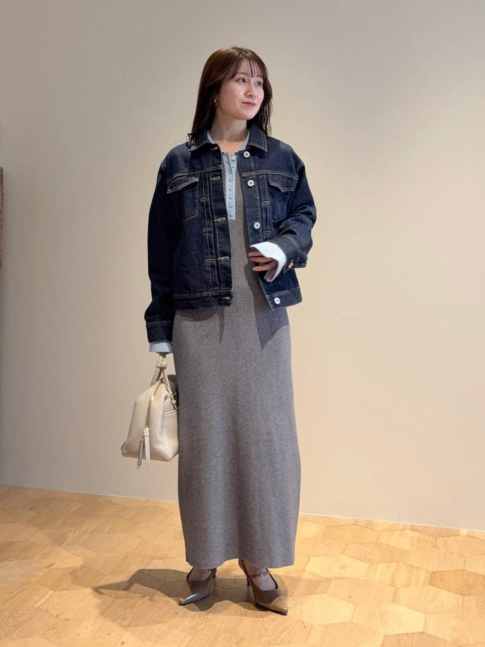 ベージュ系のハンドバッグ、グレー系のワンピース、ブルー系のデニムジャケットを着用したレディースの春コーディネートの1枚目の写真