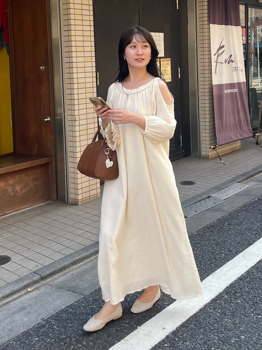 ブラウン系のショルダーバッグ、ホワイト系のワンピース、ベージュ系のキーホルダーを着用したレディースの夏コーディネートの1枚目の写真