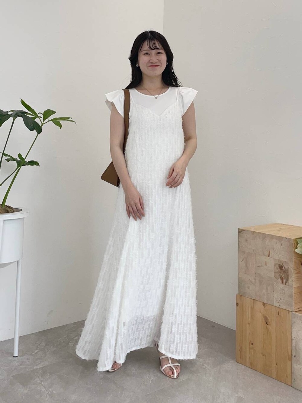 ホワイト系のワンピース、ホワイト系のTシャツ/カットソー、ブラウン系のショルダーバッグを着用したレディースの春コーディネートの1枚目の写真