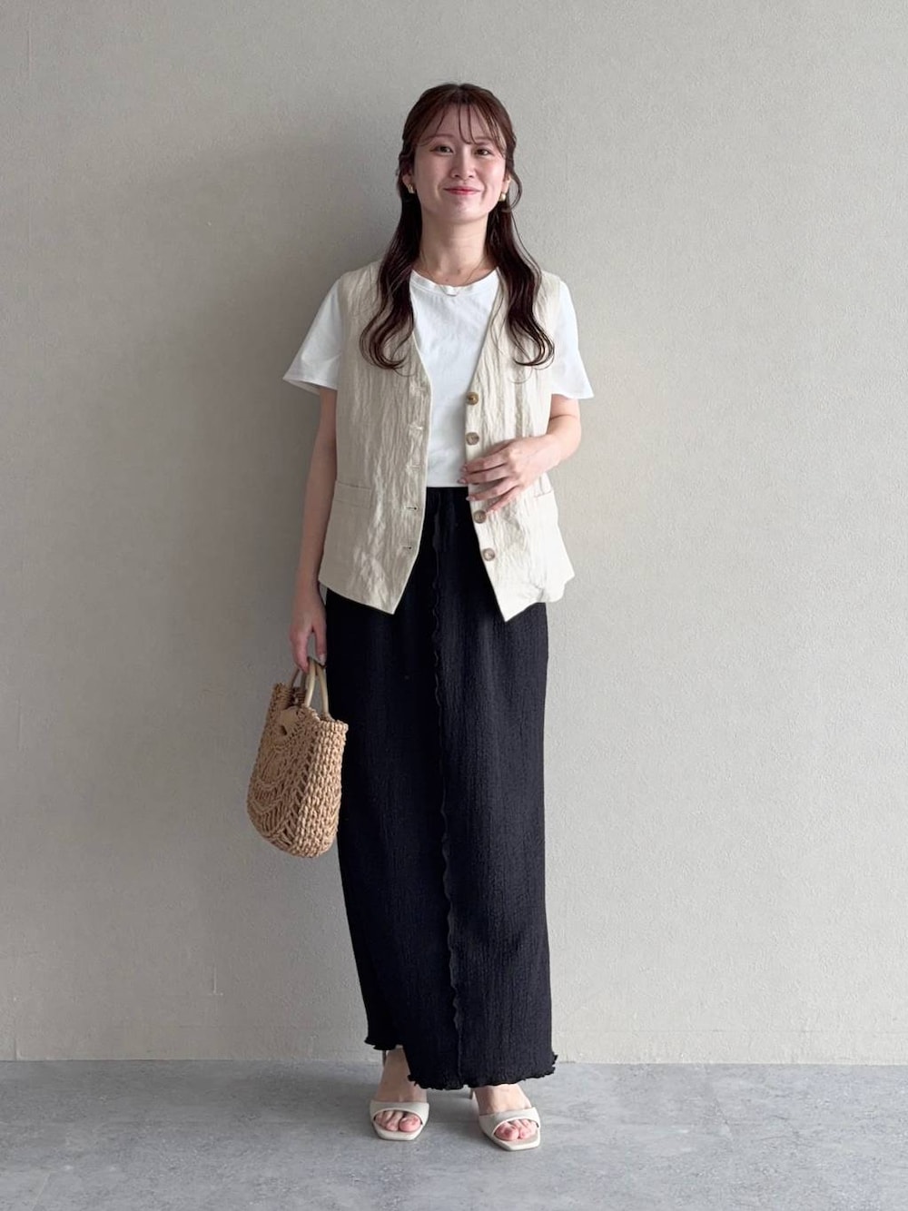 ブラック系のスカート、ホワイト系のサンダル、ホワイト系のTシャツ/カットソーを着用したレディースの夏コーディネートの1枚目の写真
