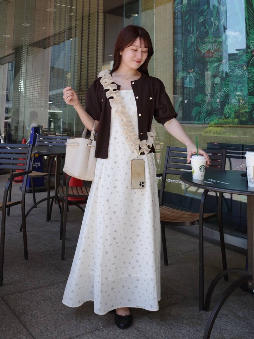 ブラウン系のカーディガン/ボレロ、ホワイト系のワンピース、ホワイト系のスマホグッズを着用したレディースの夏コーディネートの1枚目の写真