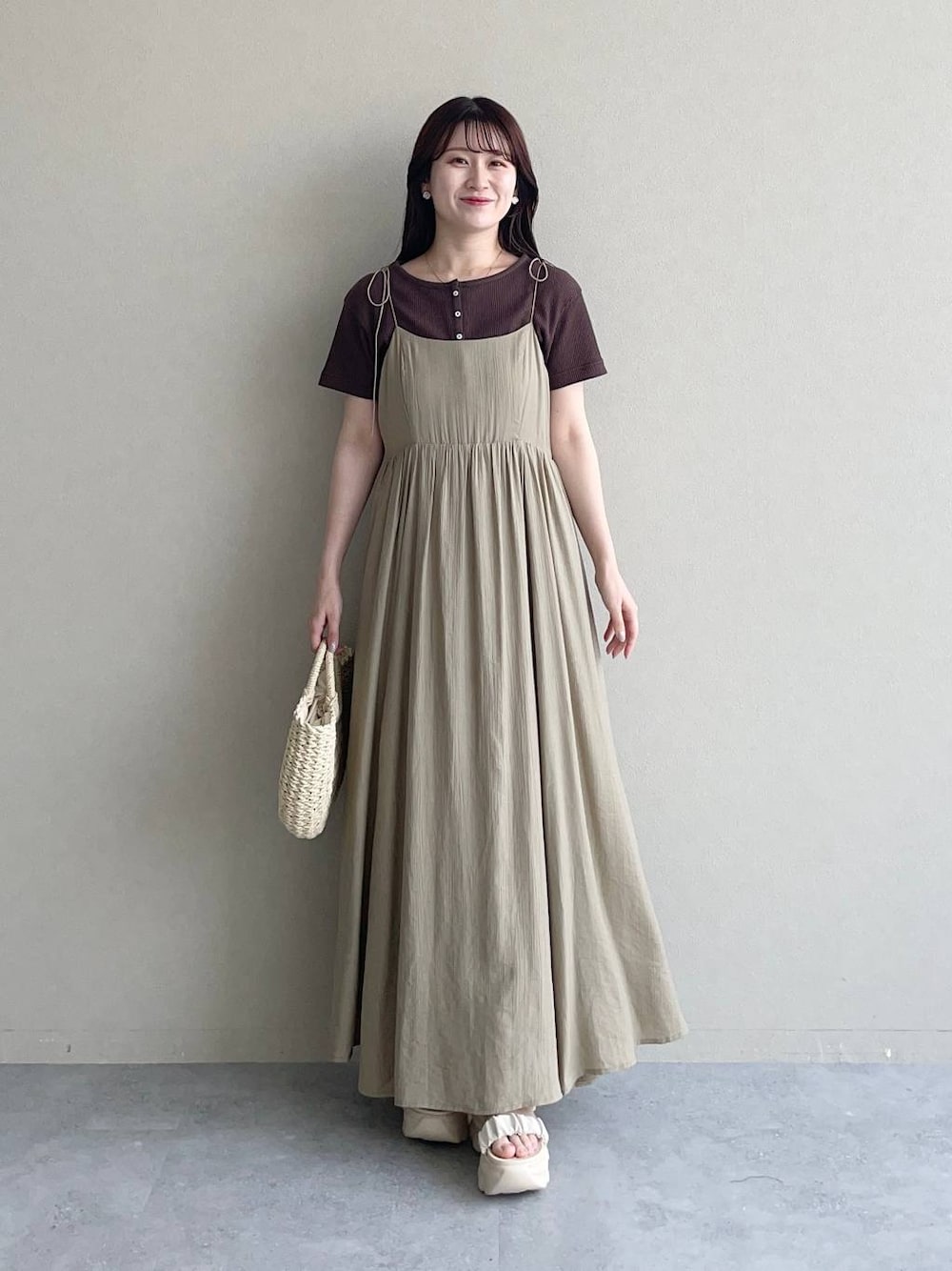 ホワイト系のサンダル、ベージュ系のワンピース、ベージュ系のかごバッグを着用したレディースの春コーディネートの1枚目の写真