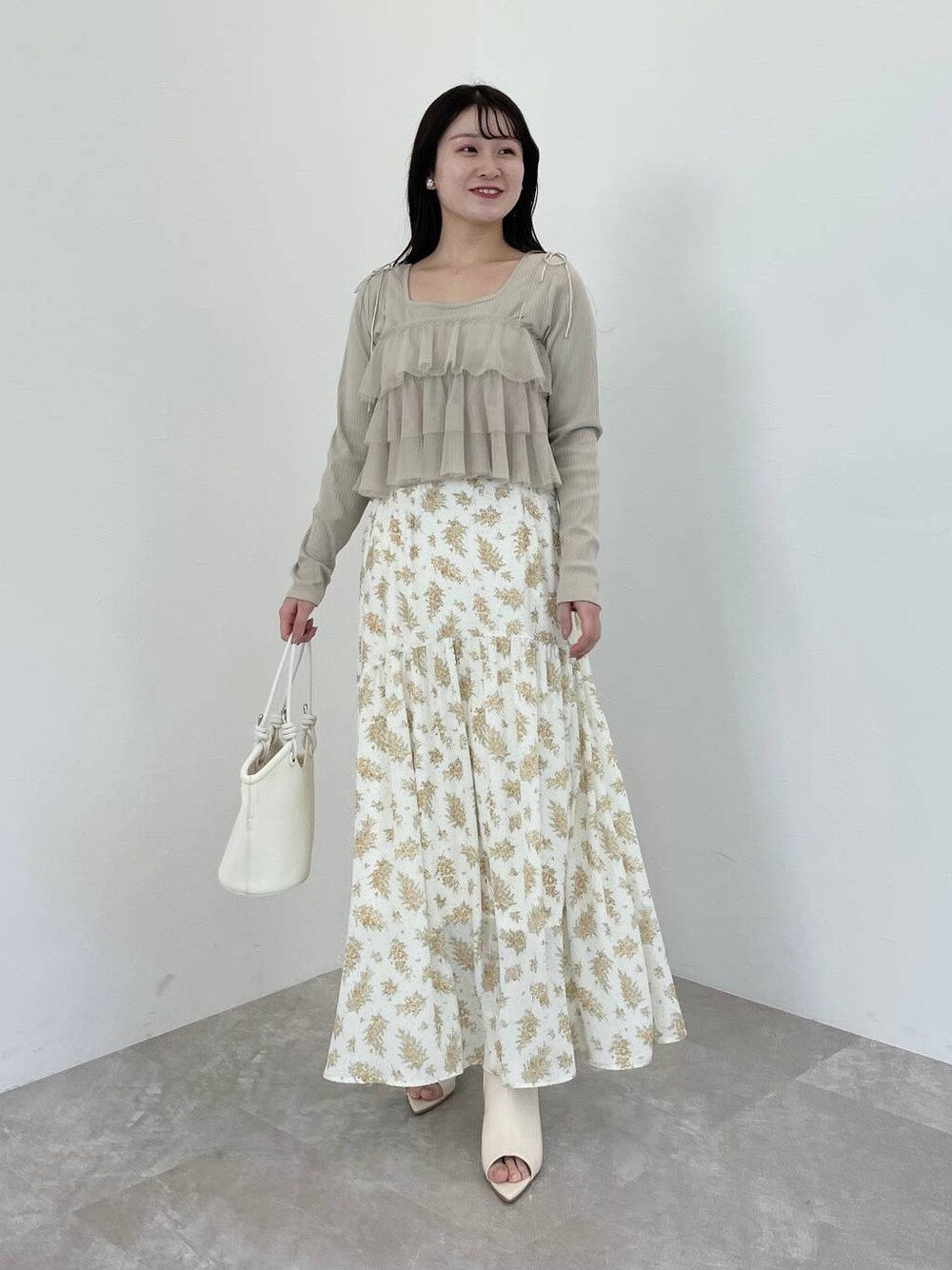 イエロー系のスカート、ベージュ系のシャツ/ブラウス、ホワイト系のブーツを着用したレディースの春コーディネートの1枚目の写真