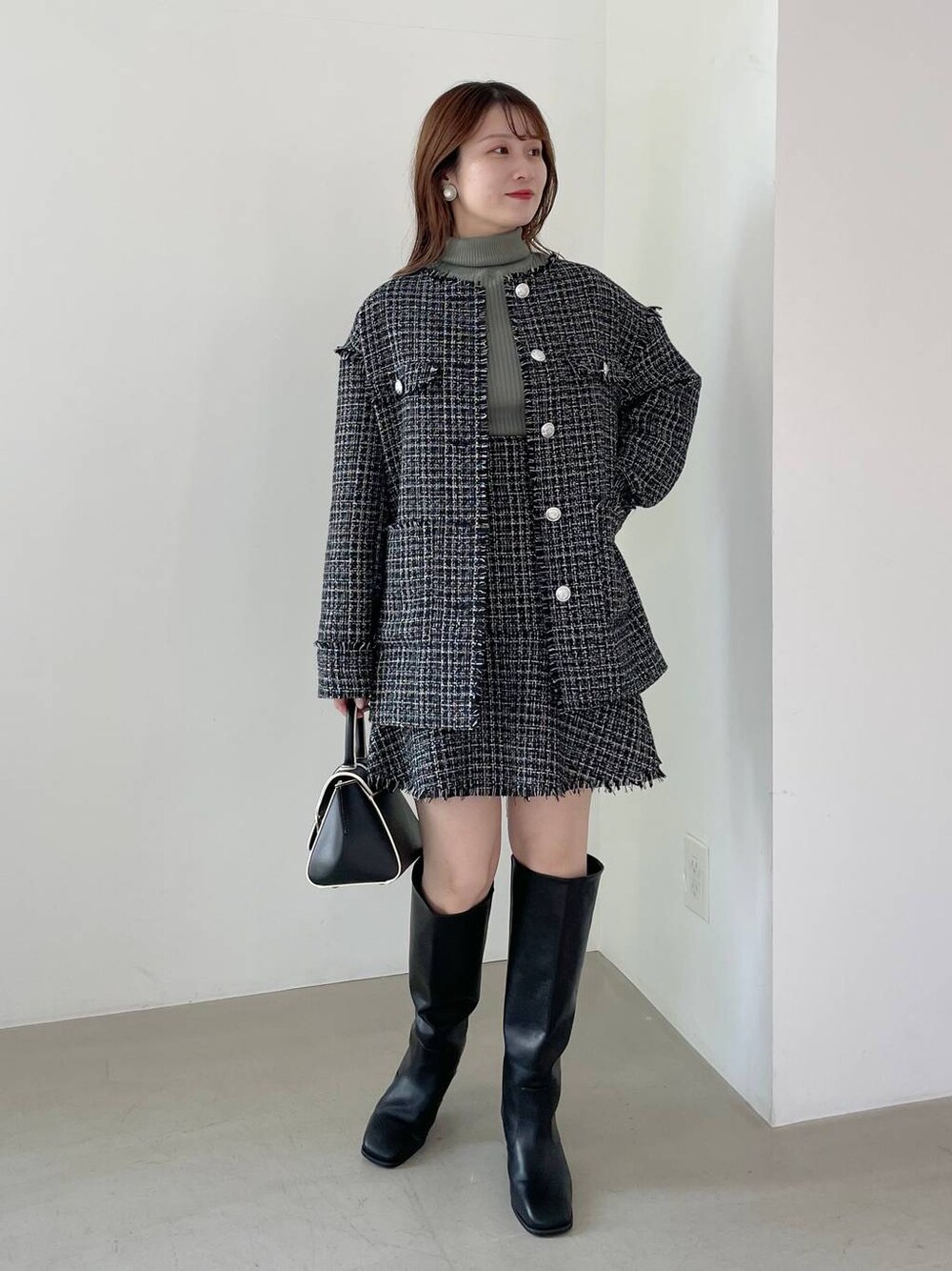 ブラック系のハンドバッグ、ブラック系のブーツ、ブラック系のノーカラージャケットを着用したレディースの秋コーディネートの1枚目の写真