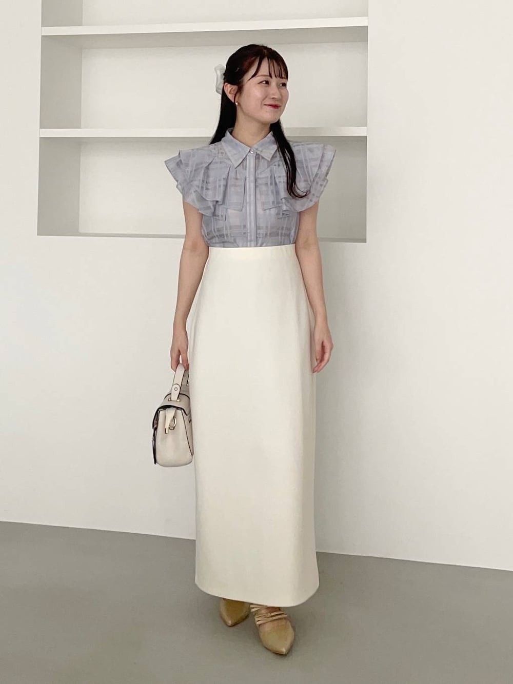 ゴールド系のパンプス、ホワイト系のショルダーバッグ、ブルー系のシャツ/ブラウスを着用したレディースの夏コーディネートの1枚目の写真