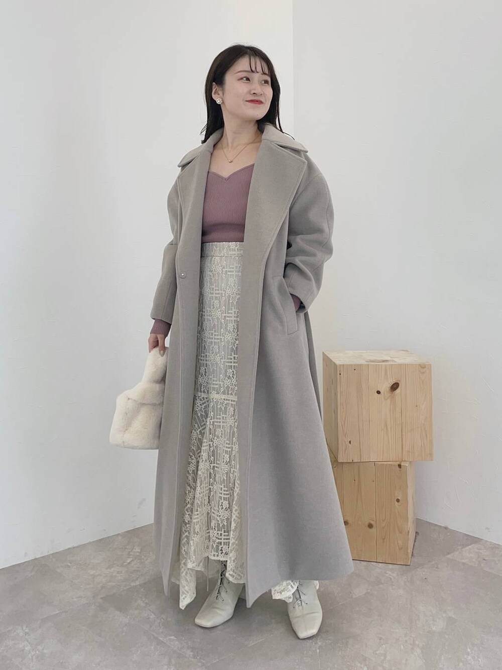 ホワイト系のブーツ、ホワイト系のスカート、ホワイト系のハンドバッグを着用したレディースの秋コーディネートの1枚目の写真