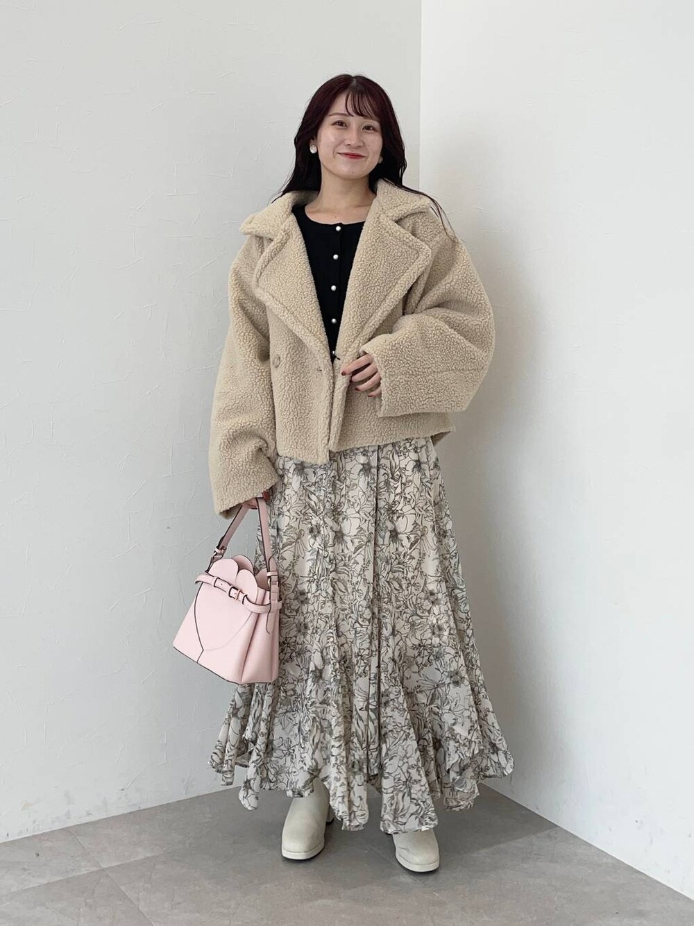 ベージュ系のピーコート、ピンク系のショルダーバッグ、ホワイト系のスカートを着用したレディースの秋コーディネートの1枚目の写真