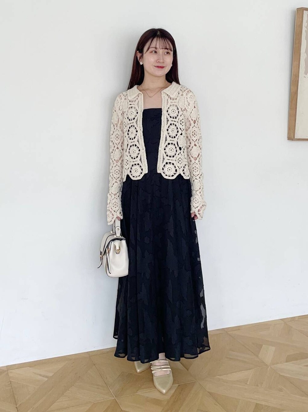 ブラック系のワンピース、ゴールド系のパンプス、ホワイト系のショルダーバッグを着用したレディースの夏コーディネートの1枚目の写真