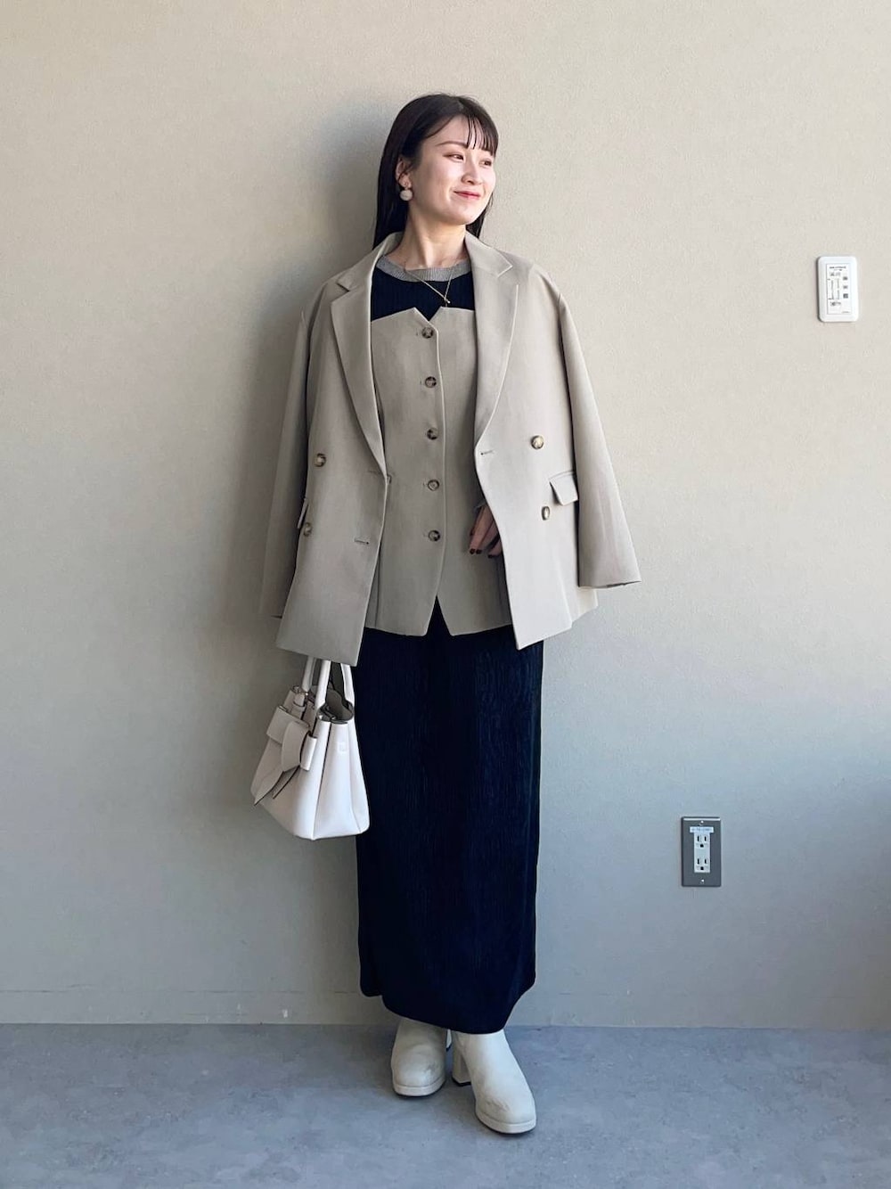 ホワイト系のブーツ、ブラック系のスカート、ホワイト系のショルダーバッグを着用したレディースの冬コーディネートの1枚目の写真