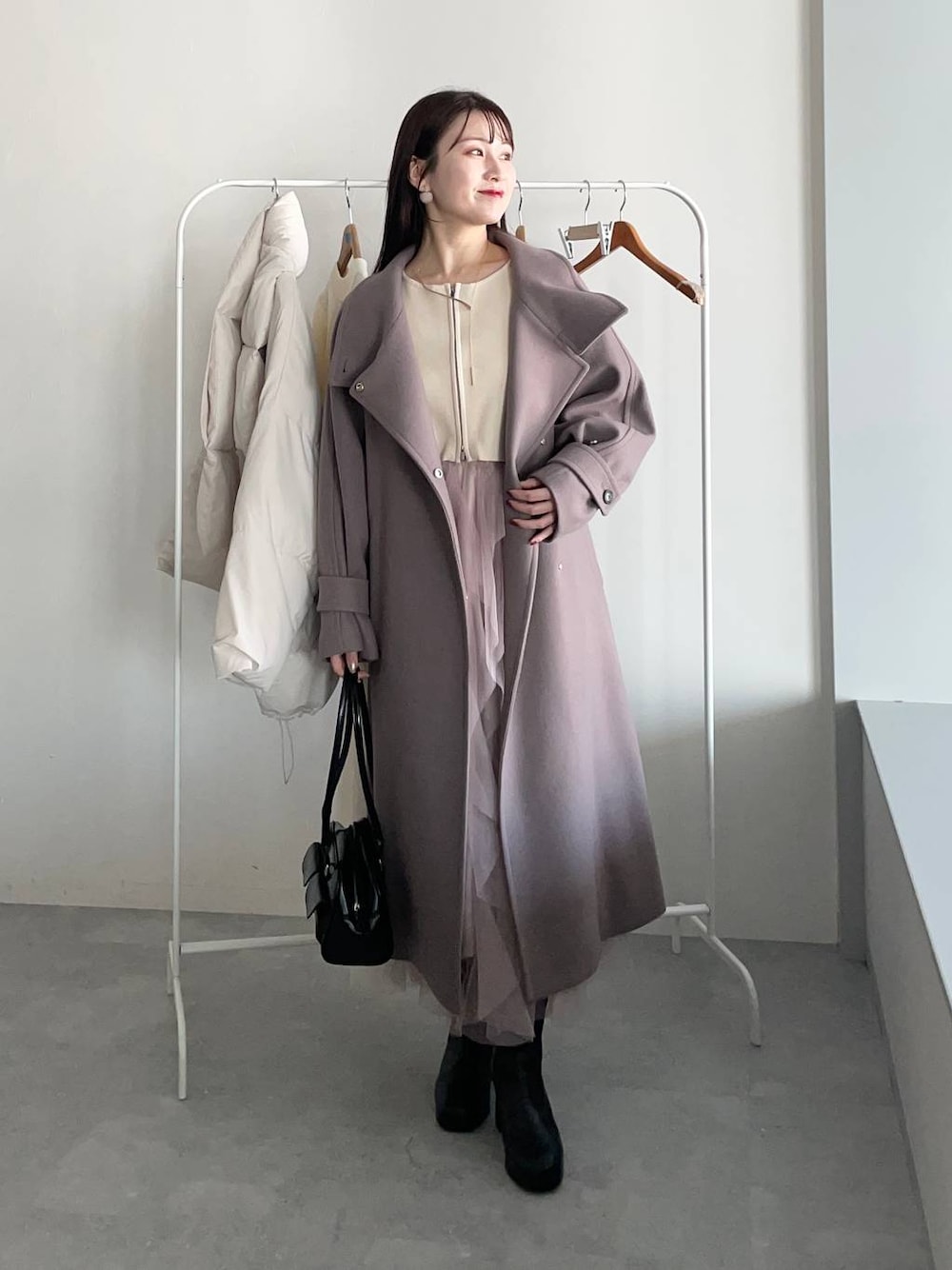 ブラウン系のチェスターコート、ブラック系のブーツ、ホワイト系のワンピースを着用したレディースの冬コーディネートの1枚目の写真