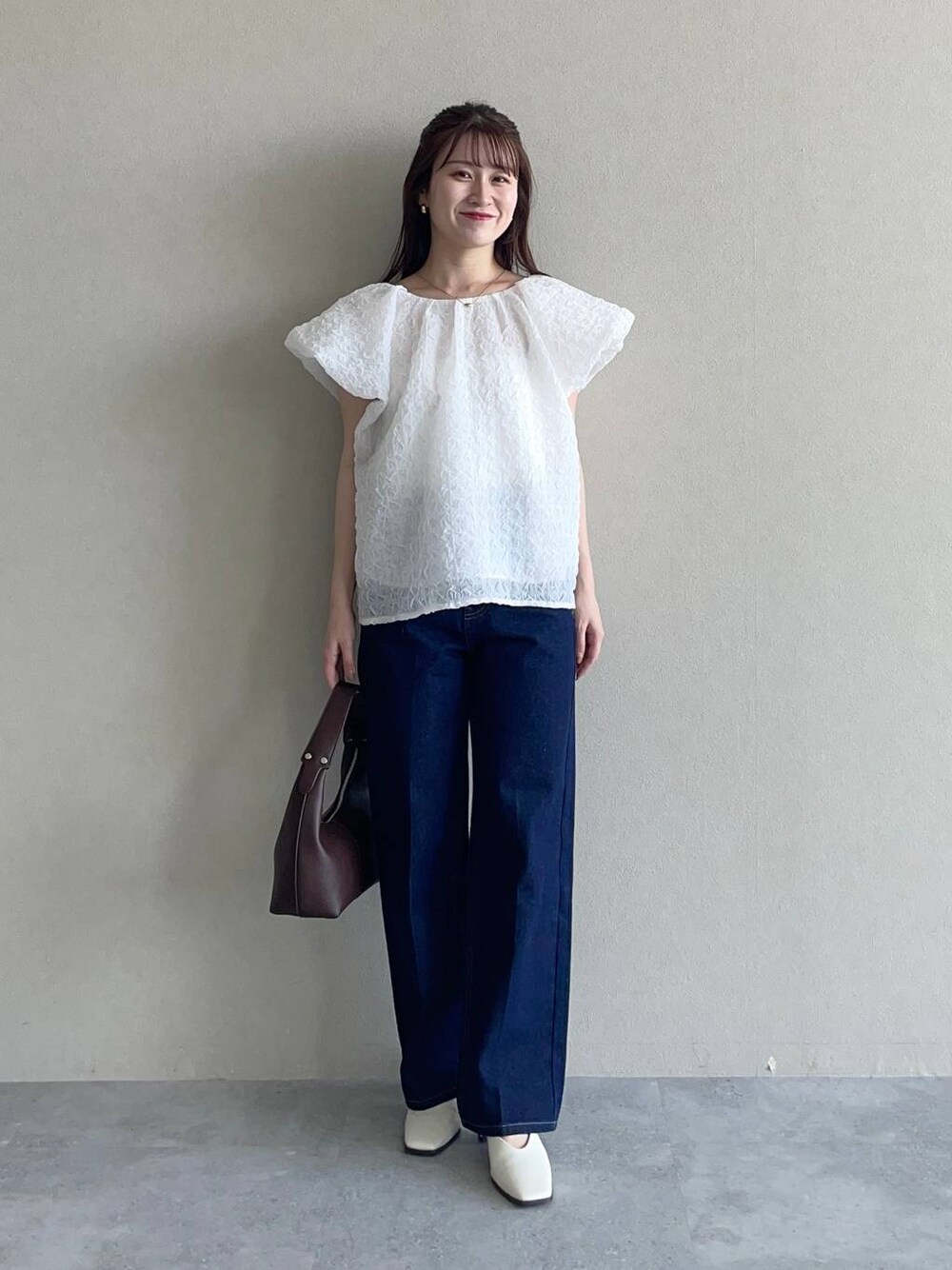 ブラウン系のショルダーバッグ、ブルー系のデニムパンツ、ホワイト系のシャツ/ブラウスを着用したレディースの夏コーディネートの1枚目の写真