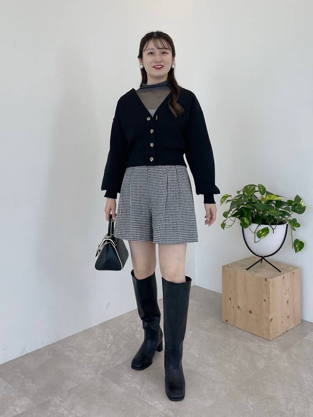 ブラック系のハンドバッグ、ブラック系のブーツ、グレー系のTシャツ/カットソーを着用したレディースの秋コーディネートの1枚目の写真