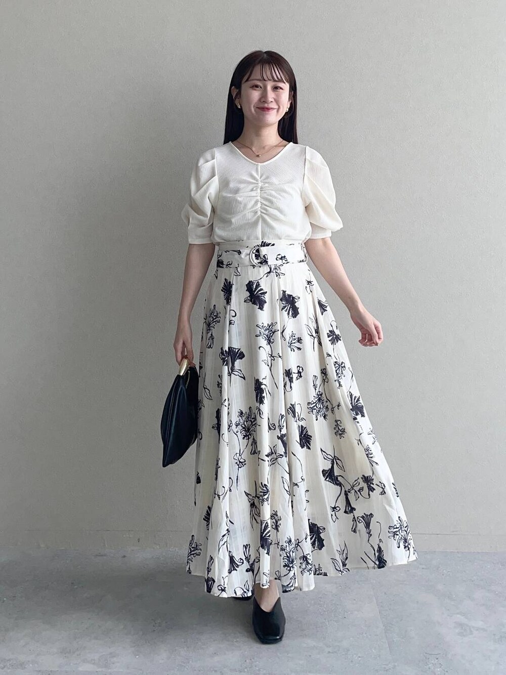 ブラック系のハンドバッグ、ホワイト系のTシャツ/カットソー、ホワイト系のスカートを着用したレディースの秋コーディネートの1枚目の写真