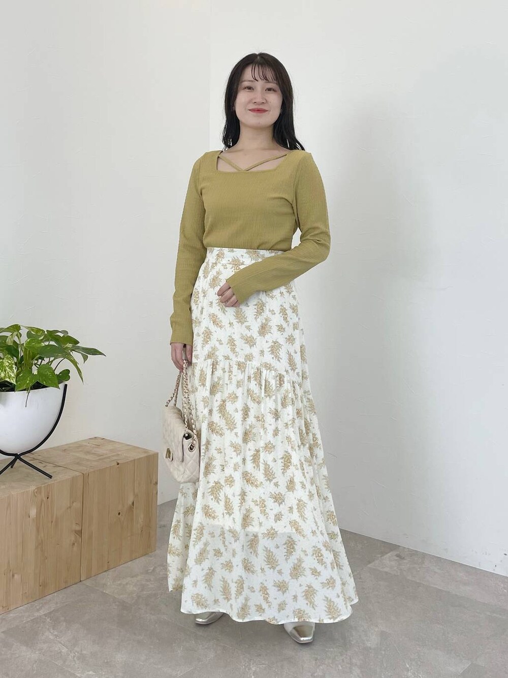 シルバー系のバレエシューズ、イエロー系のスカート、ホワイト系のショルダーバッグを着用したレディースの春コーディネートの1枚目の写真