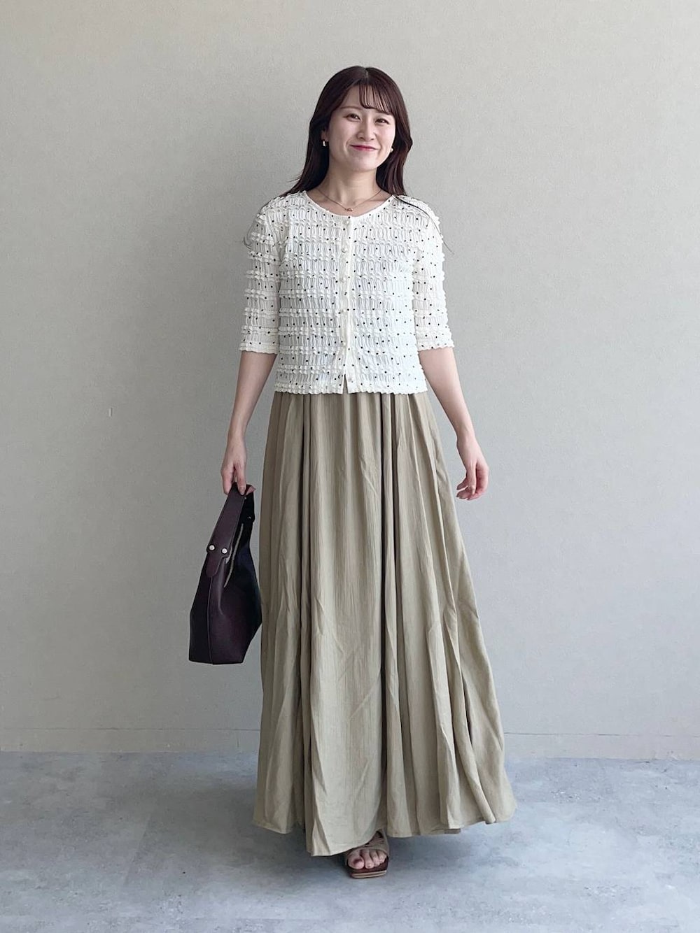 ブラウン系のサンダル、ブラウン系のショルダーバッグ、ベージュ系のワンピースを着用したレディースの夏コーディネートの1枚目の写真