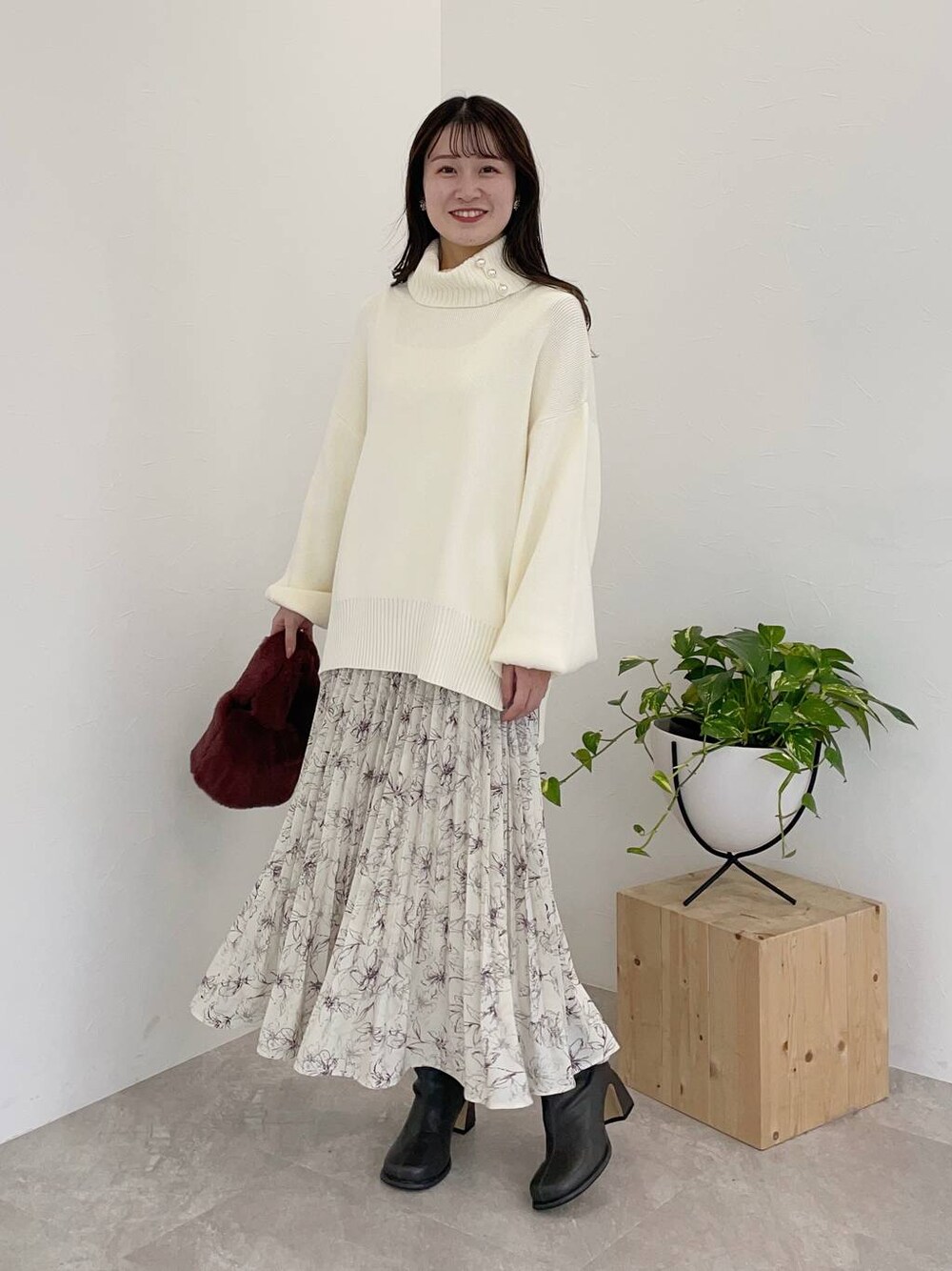 グレー系のブーツ、ピンク系のハンドバッグ、ホワイト系のスカートを着用したレディースの冬コーディネートの1枚目の写真