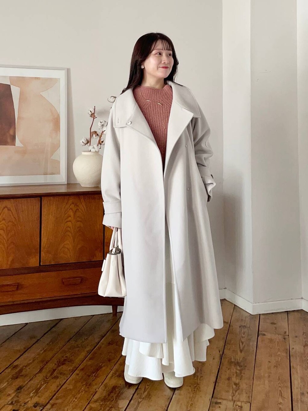 ホワイト系のチェスターコート、ホワイト系のブーツ、ホワイト系のスカートを着用したレディースの冬コーディネートの1枚目の写真
