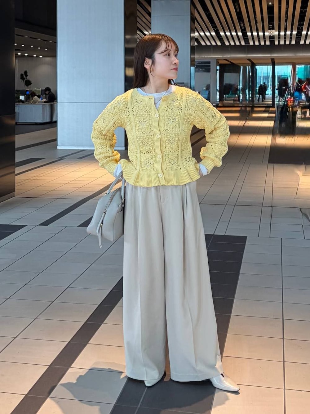 ホワイト系のTシャツ/カットソー、ベージュ系のハンドバッグ、イエロー系のカーディガン/ボレロを着用したレディースの冬コーディネートの1枚目の写真