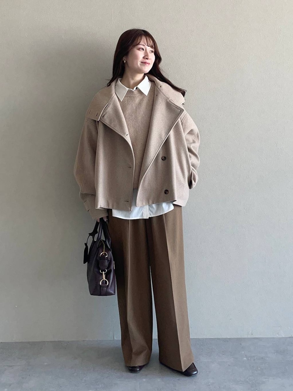 ベージュ系のピーコート、ベージュ系のニット/セーター、ブラウン系のボストンバッグを着用したレディースの冬コーディネートの1枚目の写真