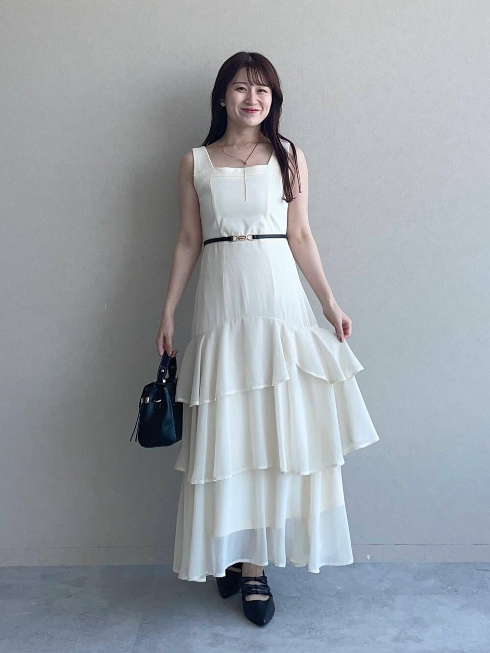 ブラック系のパンプス、ブラック系のショルダーバッグ、ホワイト系のワンピースを着用したレディースの夏コーディネートの1枚目の写真
