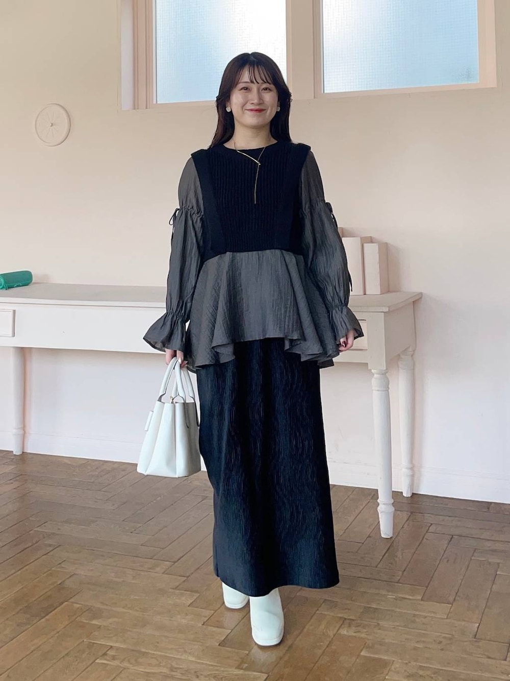 ホワイト系のブーツ、ブラック系のスカート、ブラック系のシャツ/ブラウスを着用したレディースの冬コーディネートの1枚目の写真