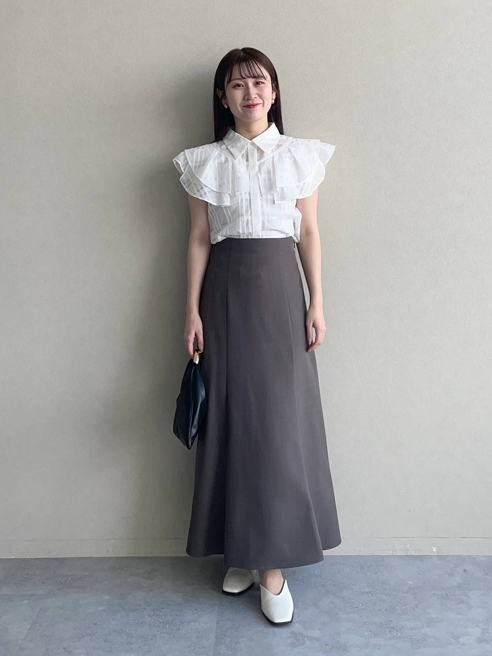 ブラック系のハンドバッグ、ホワイト系のシャツ/ブラウス、ブラウン系のスカートを着用したレディースの夏コーディネートの1枚目の写真