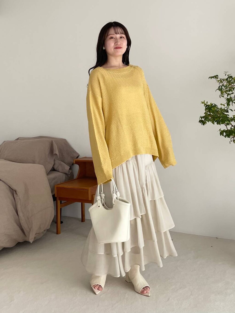 ホワイト系のスカート、イエロー系のTシャツ/カットソー、ホワイト系のブーツを着用したレディースの春コーディネートの1枚目の写真