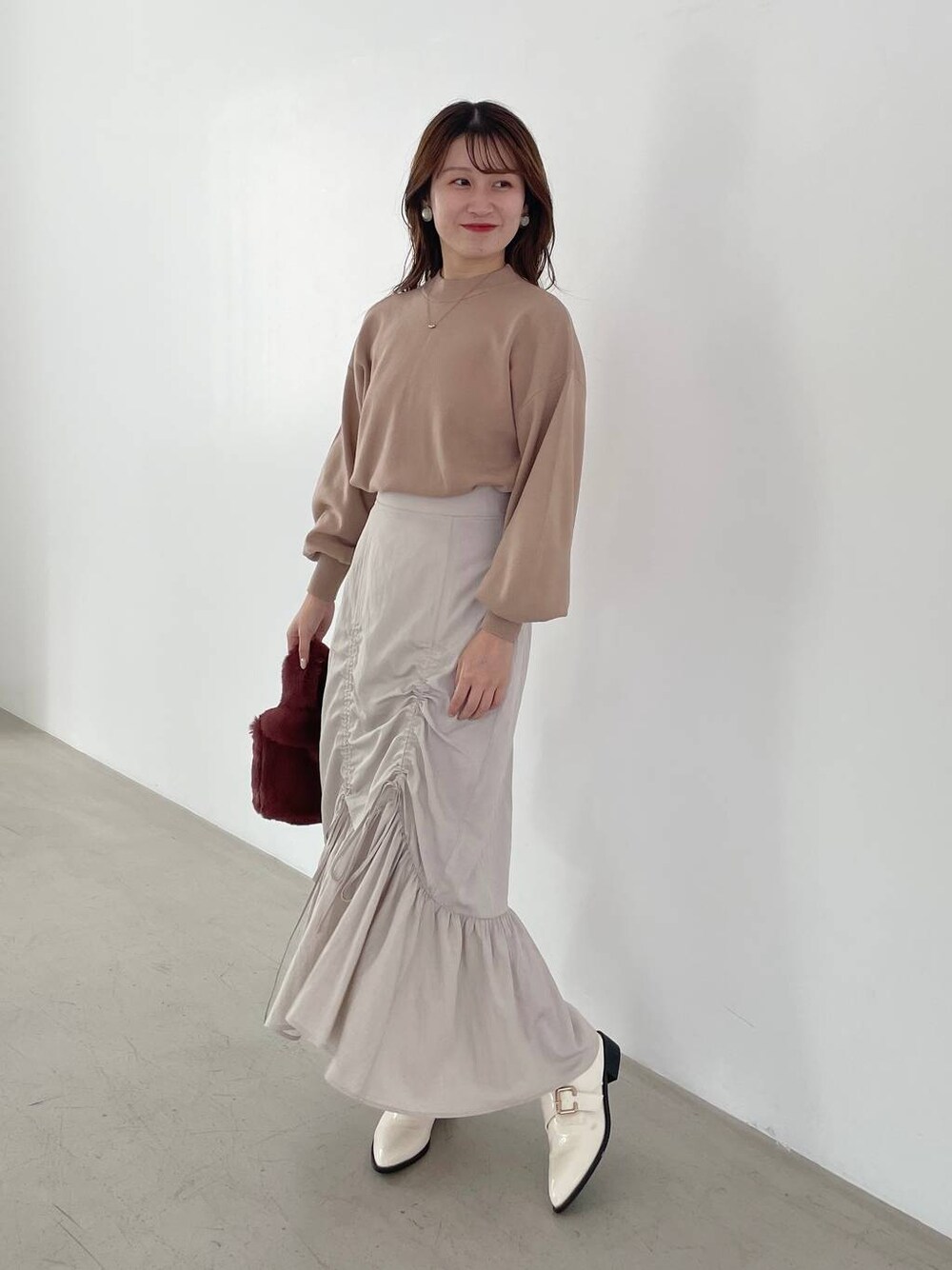 ホワイト系のその他シューズ、ブラウン系のニット/セーター、ピンク系のハンドバッグを着用したレディースの秋コーディネートの1枚目の写真